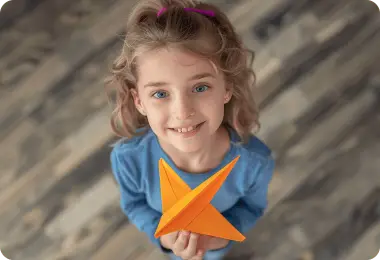 Girl holding an orange paper plane